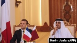 French President Emmanuel Macron (L) and Qatari Emir Sheikh Tamim bin Hamad al-Thani (R) watch as their foreign ministers sign bilateral agreements in the capital Doha, December 7, 2017