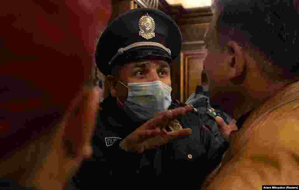 Полицейский разговариевает с протестующими внутри здания парламента.&nbsp;