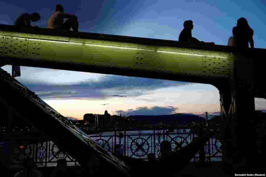 Buda Castle is seen in the background as people sit on Liberty Bridge in Budapest, Hungary. (Reuters/Bernadett Szabo)