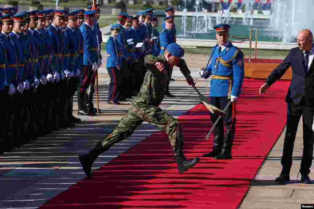 A Serbian soldier holding a broom jumps over the red carpet ahead of a welcoming ceremony for European Council President Antonio Costa, in Belgrade.