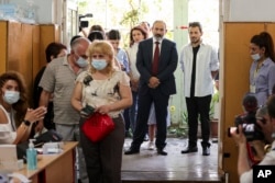 Prime Minister Nikol Pashinian (center) stands in line to vote at a polling station during parliamentary elections in Yerevan on June 20.