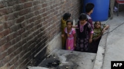 Pakistani residents stand at the site where a young woman was burnt alive by her mother in Lahore on June 8.