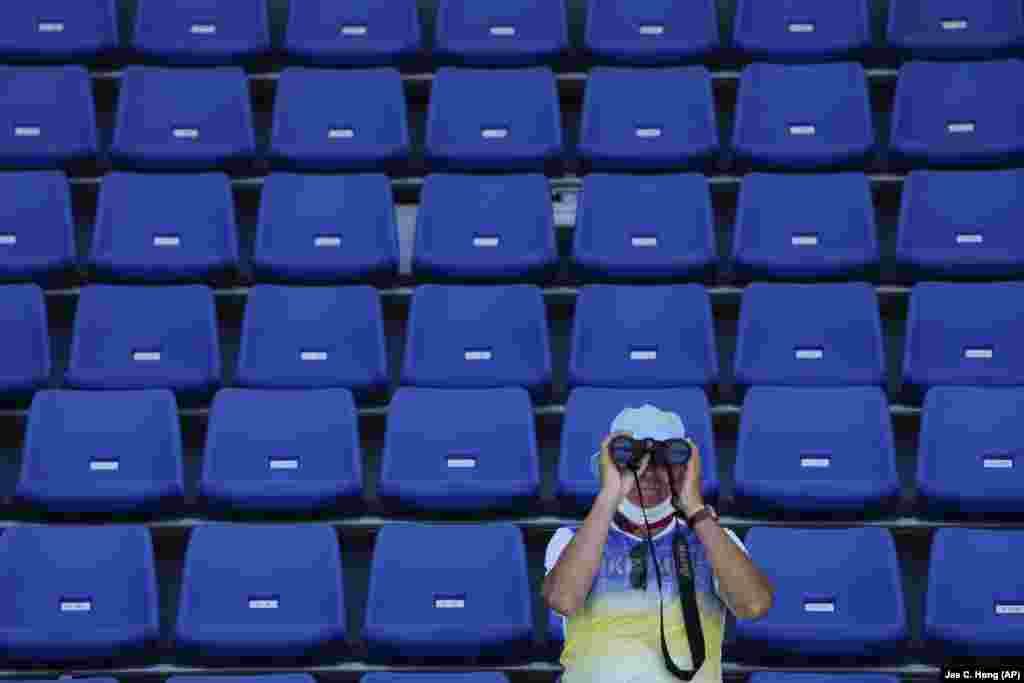 A coach from the Ukrainian rowing team looks through binoculars during a training session at the Sea Forest Waterway ahead of the 2020 Summer Olympics in Tokyo.