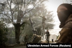 Военнослужащие 24-й механизированной бригады ВСУ устанавливают противодронные сетки над дорогой в прифронтовом городе Константиновка Донецкой области, 19 сентября 2025 года