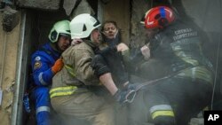 Ukrán tűzoltók mentenek ki egy sebesült nőt a romok alól az orosz rakétatámadást követően Dnyipróban 2023. január 15-én