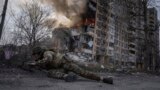 Un polițist ucrainean se ascunde în fața unui clădiri în flăcări, lovită într-un atac aerian rus la Avdiivka, Ucraina, 17 martie 2023.