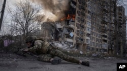 Un polițist ucrainean se ascunde în fața unui clădiri în flăcări, lovită într-un atac aerian rus la Avdiivka, Ucraina, 17 martie 2023.