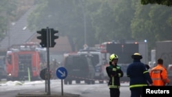 A firefighter talks on the phone as fire engines are lined up after a fire broke out at metal factory in Berlin