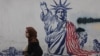 A woman walks near an anti-US mural in Tehran. 