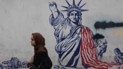 A woman walks near an anti-US mural in Tehran. 