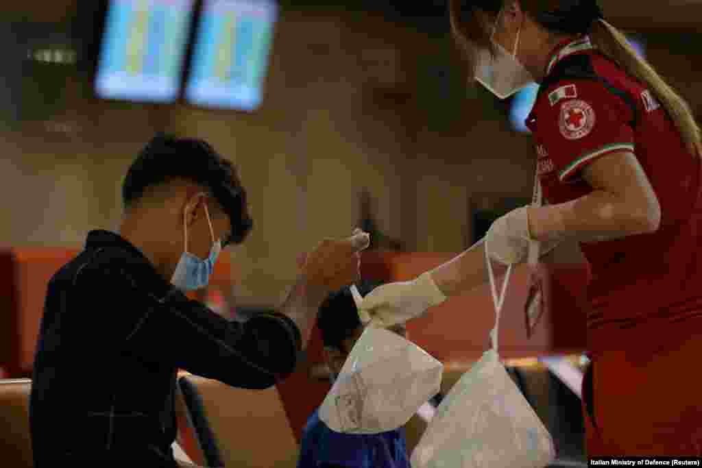 An Afghan boy receives a bag of food from a Red Cross worker after landing at Fiumicino airport in Rome on August 16.