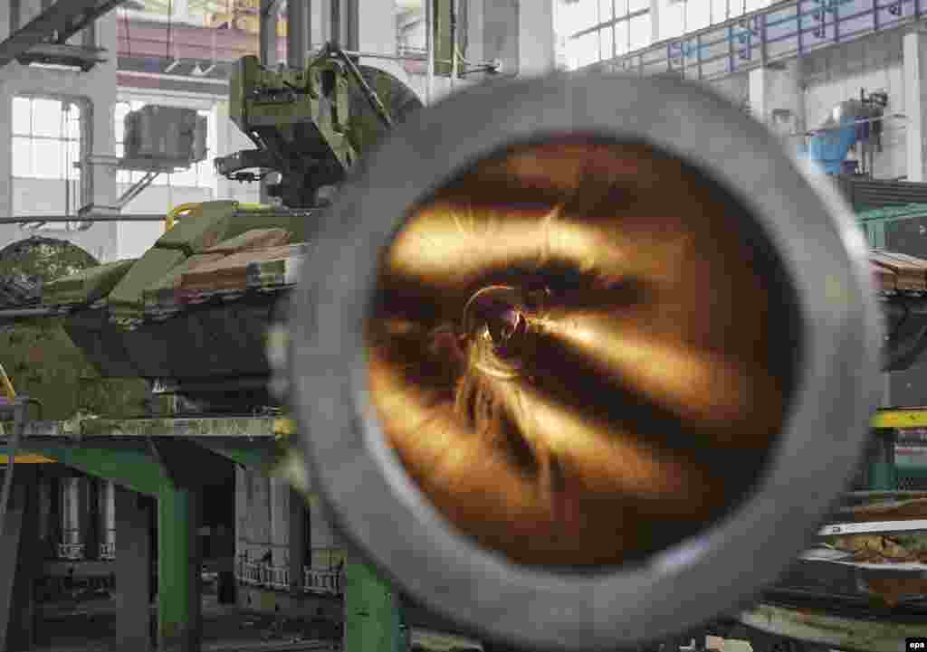 A Ukrainian worker looks through the barrel from inside a tank turret at Kharkiv&#39;s Armored Plant where T-80 tanks are being modified, in Kharkiv. (epa/Sergei Kozlov)