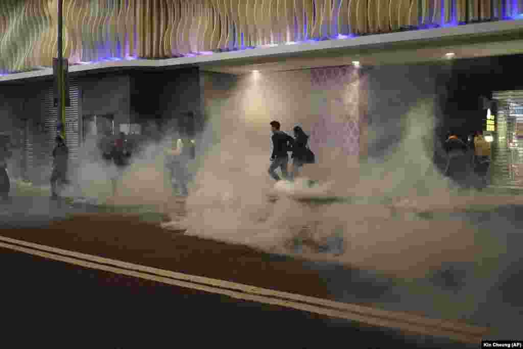 Residents react to tear gas as police and protesters confront each other on Christmas Eve in Hong Kong on December 24. (AP/Kin Cheung)