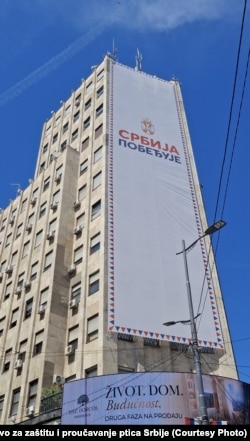 Plakat sa natpisom "Srbija pobeđuje" postavljen je na Palati Albanija 28. maja. Društva za zaštitu prirode ukazuju da je blokirao pristup gnezdima retke zaštićene ptice -bele čiope.