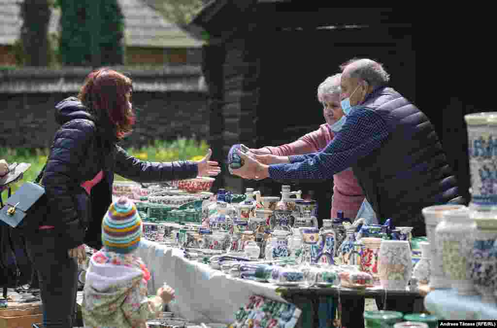 Artiști artizani vând vase din ceramică pictate manual cu motive populare.