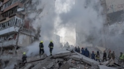Echipele de salvare acționează la locul unui bloc de locuințe parțial distrus în urma atacurilor cu drone și rachete rusești asupra Kievului, pe 14 mai 2026