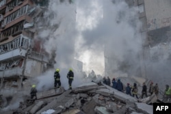 Spasioci rade na zgradi koja je djelimično uništena u ruskim napadima na Kijev 14. maja