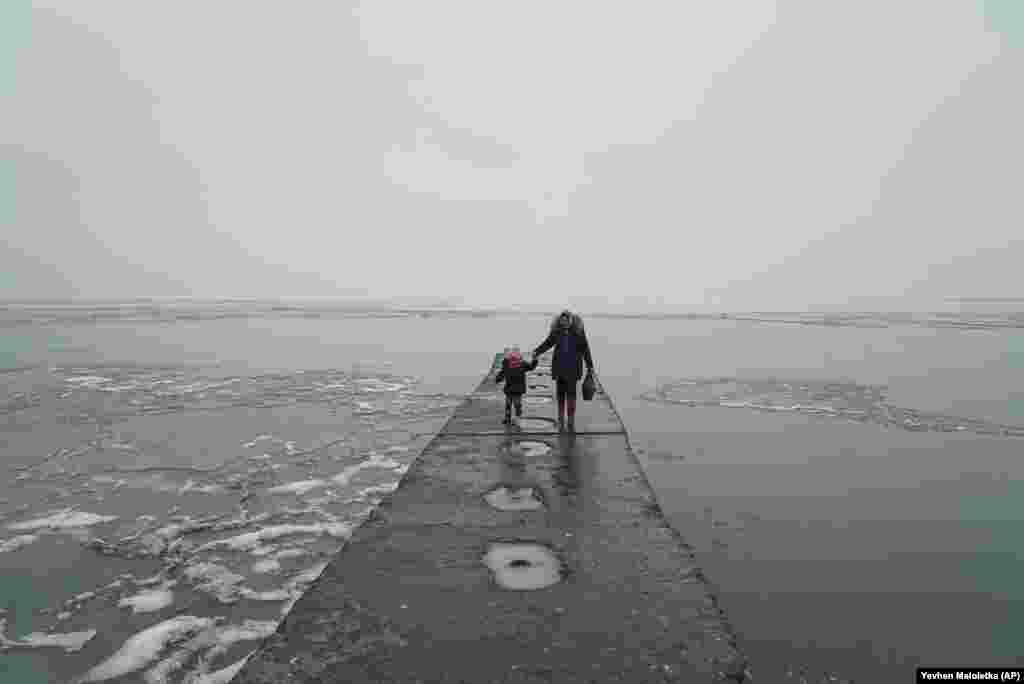 A woman and her child walk at the harbor at Mariupol on the Sea of Azov in eastern Ukraine. (AP/Evgeniy Maloletka)