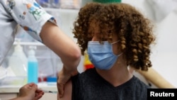 Un adolescent primește o doză de vaccin împotriva coronavirusului la Tel Aviv. Varianta Delta se transmite în special la tineri și adolescenți și prin intermediul lor.