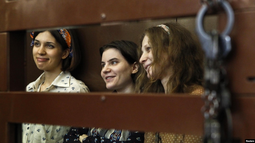 Pussy Riot members Nadezhda Tolokonnikova (from left to right), Yekaterina Samutsevich, and Maria Alyokhina look out from the defendents' cell in a court in Moscow.