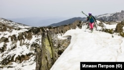 Скиор в ски обувки със ски, закачени на раницата, се качва към връх Бъндеришки чукар в Пирин