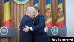 Prim-miniștri Bolojan și Dorin Recean, îmbrățișându-se în timpul unei apariții în fața presei, la Casa Guvernului din Chișnău, pe 23 august 