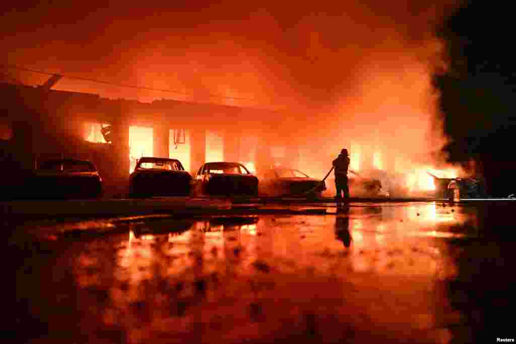 A Ukrainian firefighter battles a blaze at a private enterprise hit by a Russian drone strike in Zaporizhzhya.