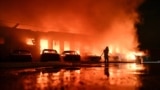 A Ukrainian firefighter battles a blaze at a private enterprise hit by a Russian drone strike in Zaporizhzhya. 