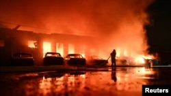A Ukrainian firefighter battles a blaze at a private enterprise hit by a Russian drone strike in Zaporizhzhya. 