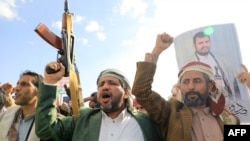 Йеменские мужчины размахивают оружием и держат портреты лидера хуситов Абдул-Малика аль-Хуси во время акции протеста в знак солидарности с палестинским народом в контролируемой хуситами столице Йемена Сане, 5 января 2024 года
