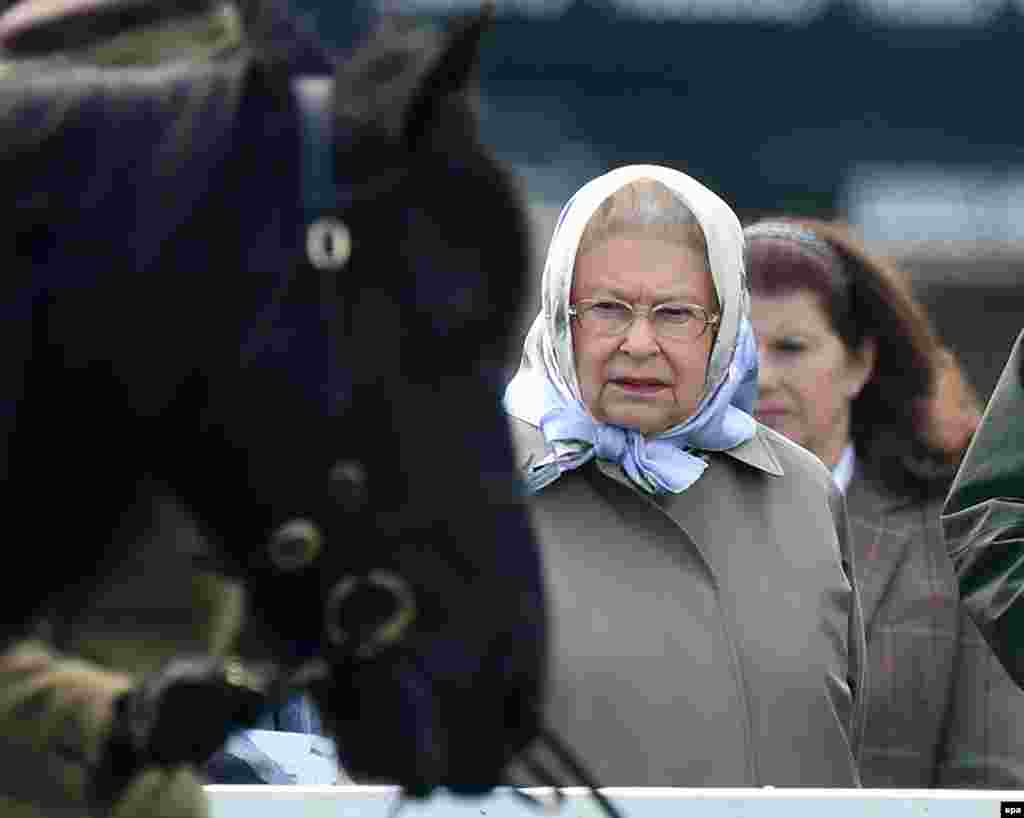 Regina Marii Britanii observă caii care concurează în timpul Windsor Royal Horse Show, în Windsor, lângă Londra, pe 13 mai 2016. Tatăl reginei, George al VI-lea, a respectat tradiția curselor de cai asociată regilor, fiind de asemenea un pasionat de creșterea animalelor de rasă. La moartea regelui, în 1952, Elisabeta a moștenit operațiunea Royal Studs din Sandringham, pe lângă grajdurile tatălui ei.&nbsp;De-a lungul vieții sale a ajuns să dețină peste 100 de cai de rasă.