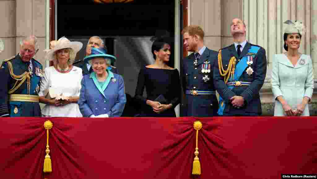 Prințul Charles al Marii Britanii, Camilla, ducesă de Cornwall, Regina Elisabeta, Meghan, ducesă de Sussex, Prințul Harry, Prințul William și Catherine, ducesă de Cambridge, urmăresc de la balconul Palatului Buckingham zborurile care marchează centenarul Forțelor Aeriene Regale, Marea Britanie, 10 iulie 2018.