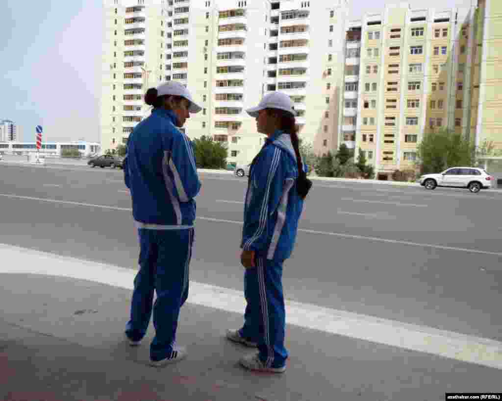 Aşgabadyň awtobus duralgalarynyň birinde awtobusa garaşyp duran sport geýimli studentler