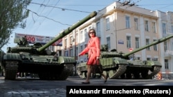 Донеччанка переходить вулицю Артема в Донецьку перед танками бойовиків на репетиції параду до 9 травня
