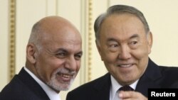 Kazakh President Nursultan Nazarbaev (R) and Afghan President Ashraf Ghani smile as they arrive for a news conference after their meeting at the Akorda presidential residence in Astana on November 20.