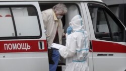 Медработник рядом с человеком в дверях машины скорой помощи.