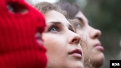 Nadejda Tolokonikova (dreapta, Maria Alyohina (centru) și un activist mascat la o conferință de presă, Soci, 20 februarie 2014