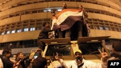 Egyptian demonstrators demanding the ouster of President Hosni Mubarak wave the national flag on top of an armored vehicle.