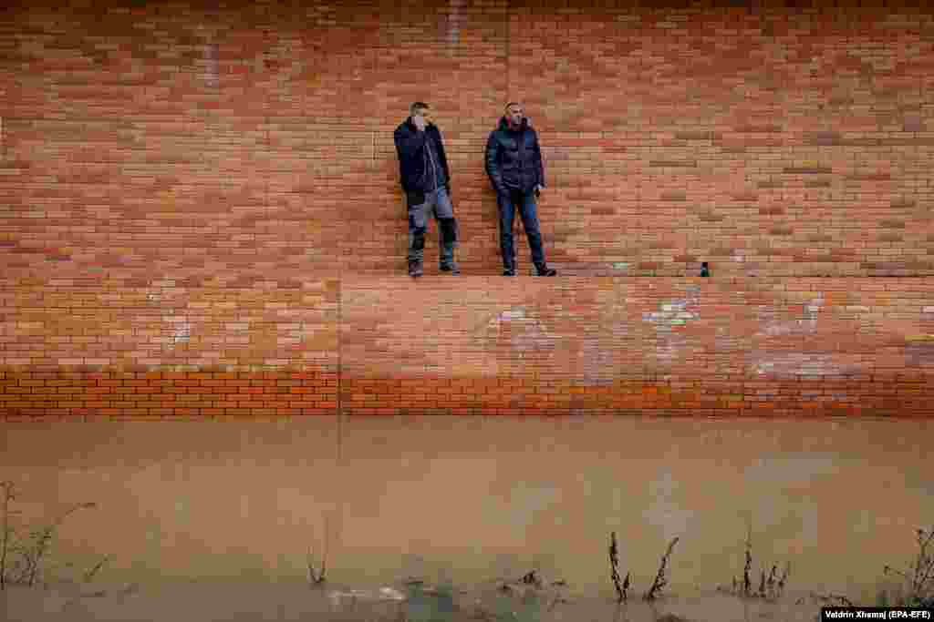 Local residents look on at floodwater due to heavy rain in the town of Fushe Kosove, Kosovo. (epa-EFE/Valdrin Xhemaj)