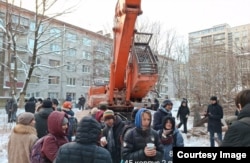 Люди собрались около техники для сноса здания