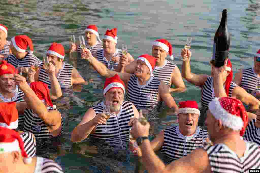 Ljudi piju šampanjac za vrijeme novogodišnjeg kupanja u Jadranskom moru u Opatiji, Hrvatska, 1. januara.