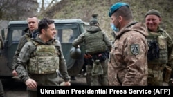 Ukrainian President Volodymyr Zelenskiy (left) visits the front line with Ukrainian troops in the Mariupol region on April 9. Zelenskiy's office said it had received no response to a request for dialogue.