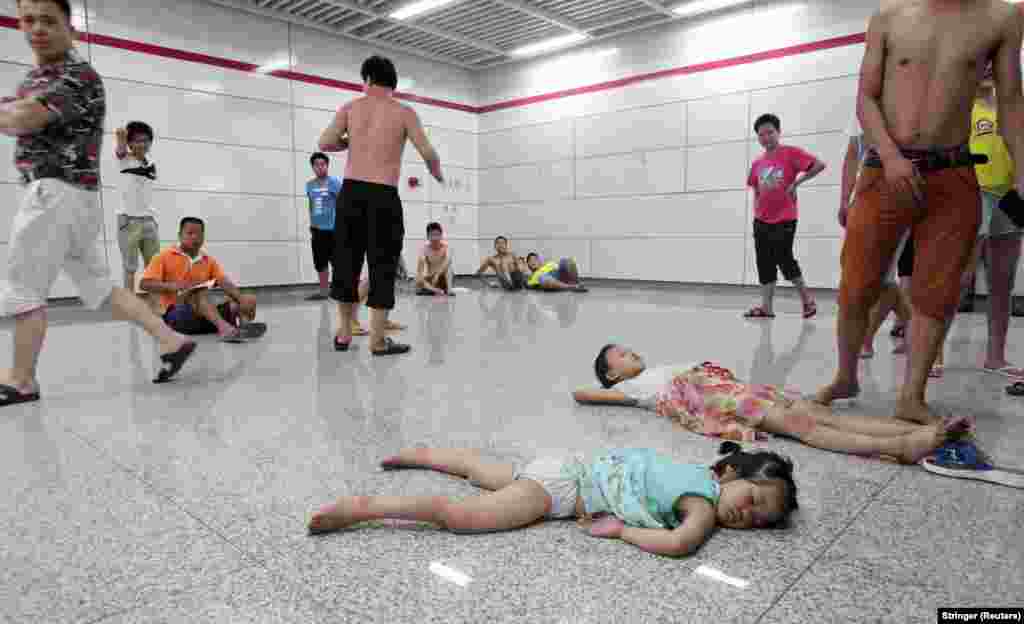 Children sleep on the floor of the Qiaosi subway station in Hangzhou in China&#39;s Zhejiang Province on July 26. Hundreds of people sought relief from the heat outside as temperatures in the city reached a high of 40 degrees Celsius and many homes were without power. 