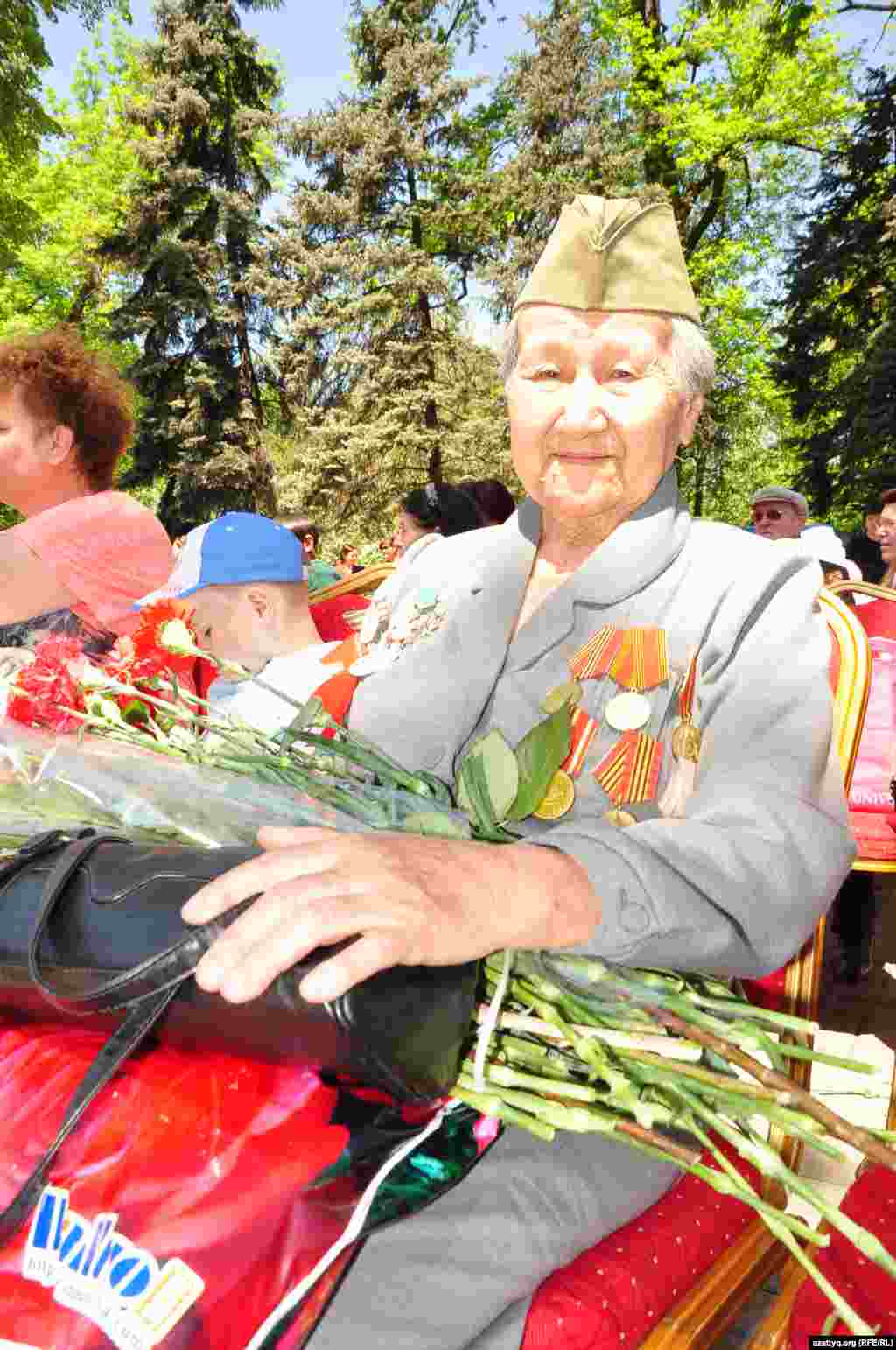 Кеудесіне медальдер тағып, басына пилотка киіп отырған әйел.