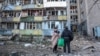 Residents stand by an apartment building in Kyiv that was damaged in a Russian missile strike on August 20.  