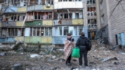 Residents stand by an apartment building in Kyiv that was damaged in a Russian missile strike on August 20.  