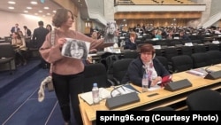 Паліна Шарэнда-Панасюк з партрэтамі беларускіх палітзьняволеных побач з супрацоўніцай МЗС Беларусі Ларысай Бельскай. Фота "Вясны"