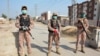 Soldiers wearing facemasks stand guard on road leading to a quarantine faciltity (R) for people returning from Iran via the Pakistan-Iran border town of Taftan to prevent the spread the coronavirus in Sukkur, a city in southern province of Sindh.