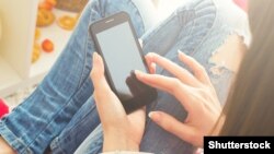 Woman at home relaxing on sofa couch reading email on mobile wifi connection/shutterstock