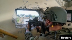 یک سرباز اسرائیلی که تفنگ خود را به جانب شهر غزه نشانه گرفته است